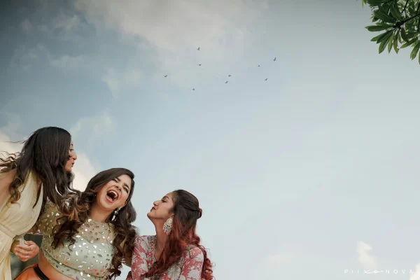 Three women express joy and happiness, smiling under a bright blue sky. Shot by Piixonova